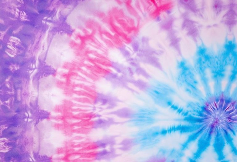 Gros plan d'un papier peint tie-dye vibrant mélangeant des teintes pastel de rose, bleu et violet, créant une ambiance douce et accueillante, finition mate, haute définition, éclairage naturel.