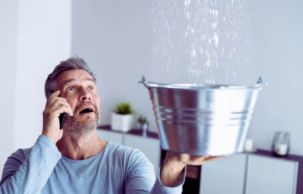Un homme qui essaie de gérer une fuite d'eau avec un seau