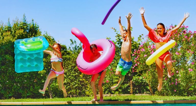 Quatre enfants joyeux sautant dans une piscine avec des bouees gonflables en ete