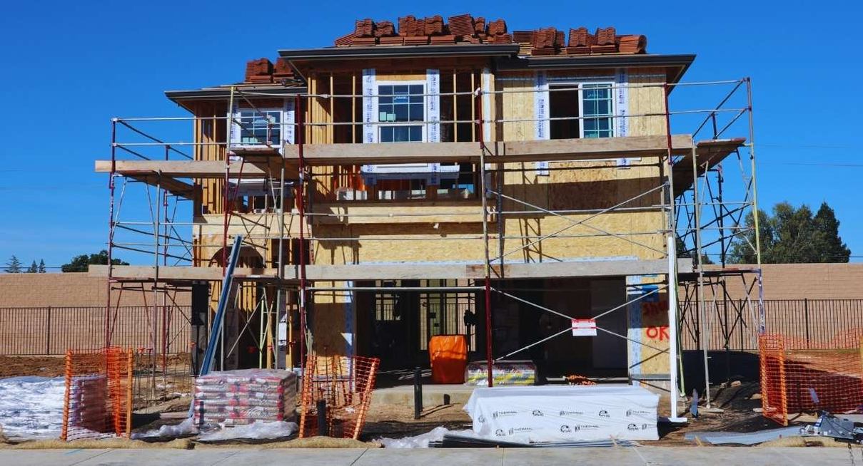 Maison individuelle en cours de construction entouree d'echafaudages sous un ciel bleu
